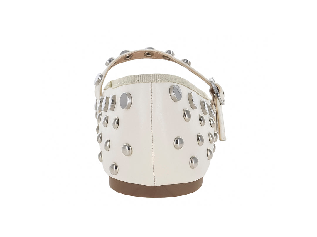 Zapato plano color off white con detalles de tachuelas plateadas y correa ajustable con hebilla.