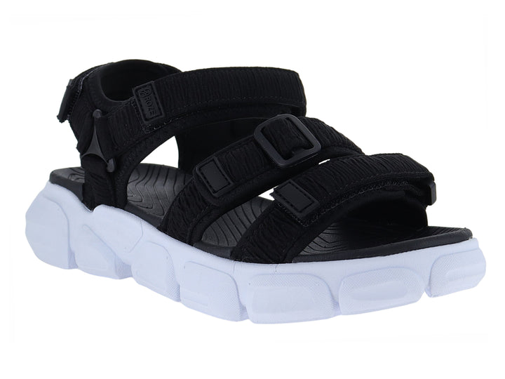 Sandalia negra con suela blanca gruesa y correas ajustables de velcro.