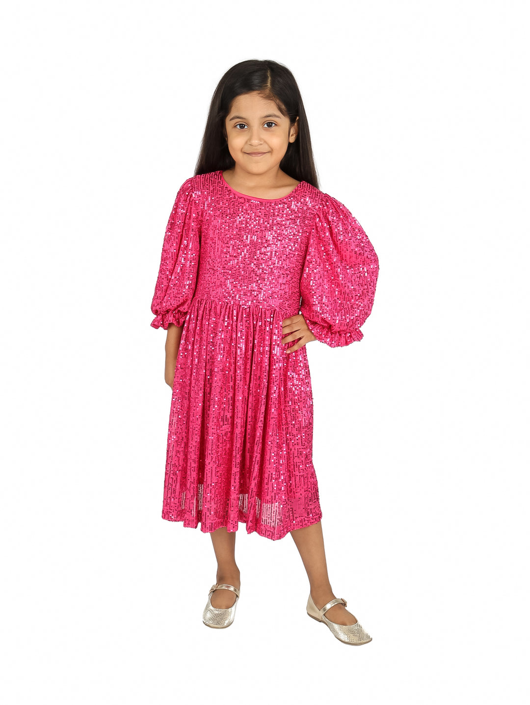 Niña vistiendo un vestido color fucsia brillante con lentejuelas y mangas abullonadas.