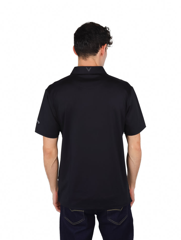 Hombre vistiendo una polo de golf color negro marca Callaway con cuello y manga corta.