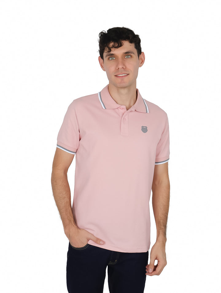 Hombre vistiendo una playera polo color rosa de manga corta con detalles blancos en el cuello y mangas.