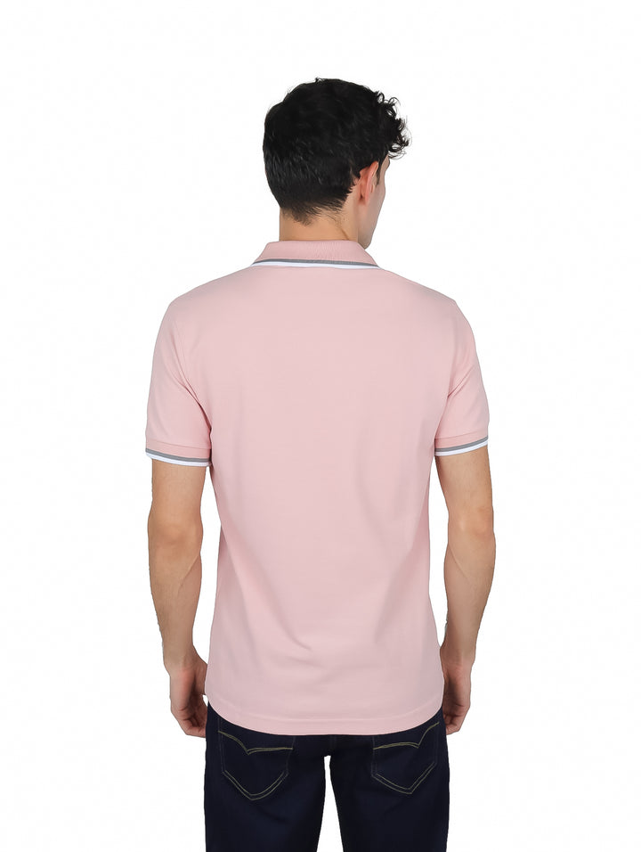 Hombre vistiendo una playera polo color rosa de manga corta con detalles blancos en el cuello y mangas.