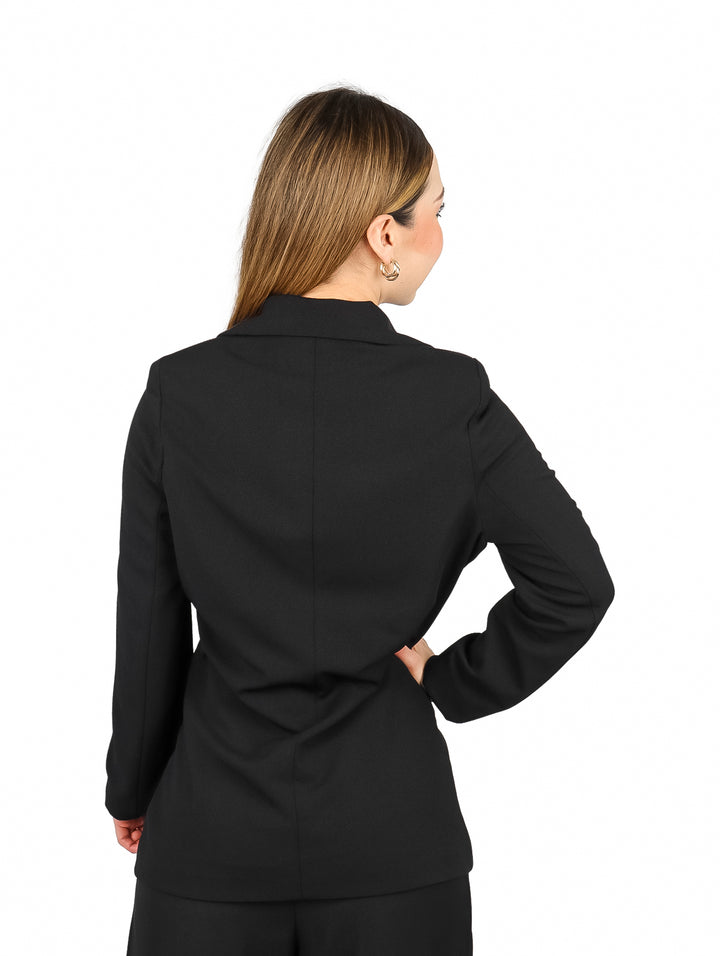 Mujer vistiendo un blazer negro elegante con botones dorados.