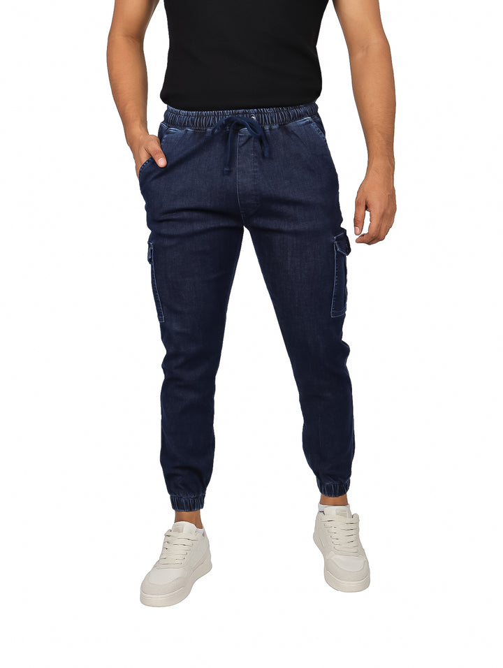 Hombre vistiendo pantalones jogger de mezclilla azul marino con bolsillos cargo y cintura elástica.