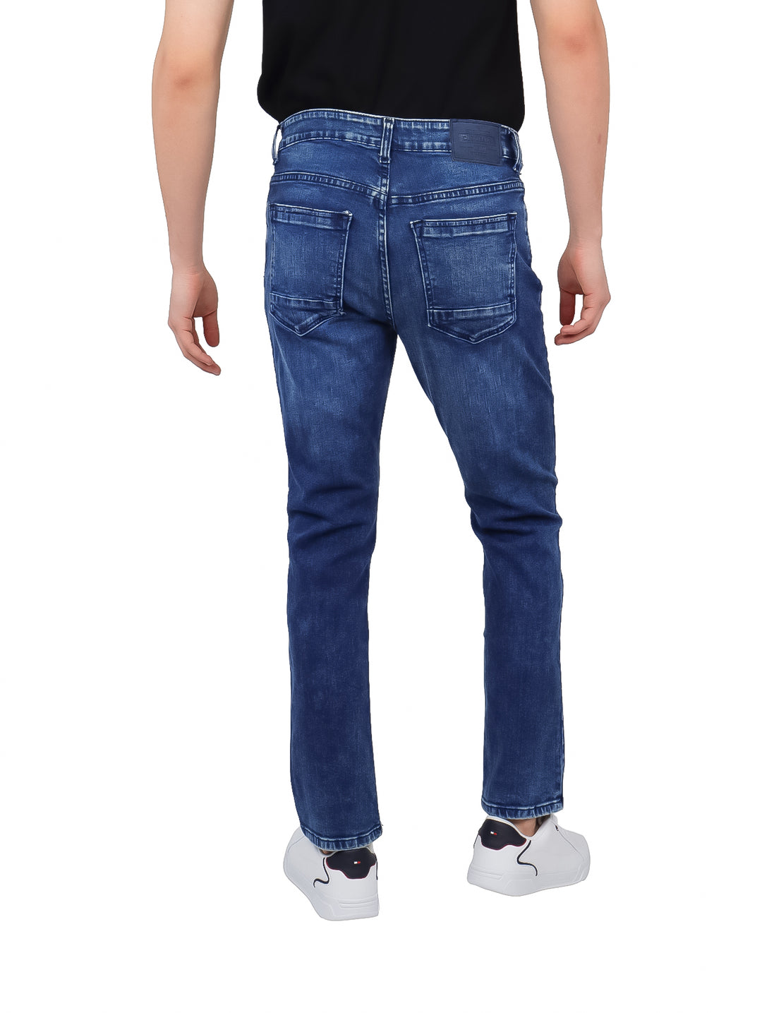 Hombre vistiendo pantalones jeans slim de color azul con efecto de lavado.