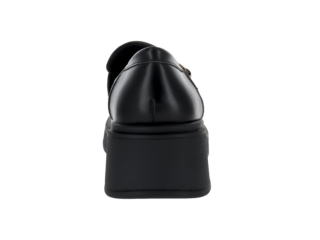Zapato tipo mocasín negro de material sintético con suela de plataforma gruesa y adorno dorado superior.