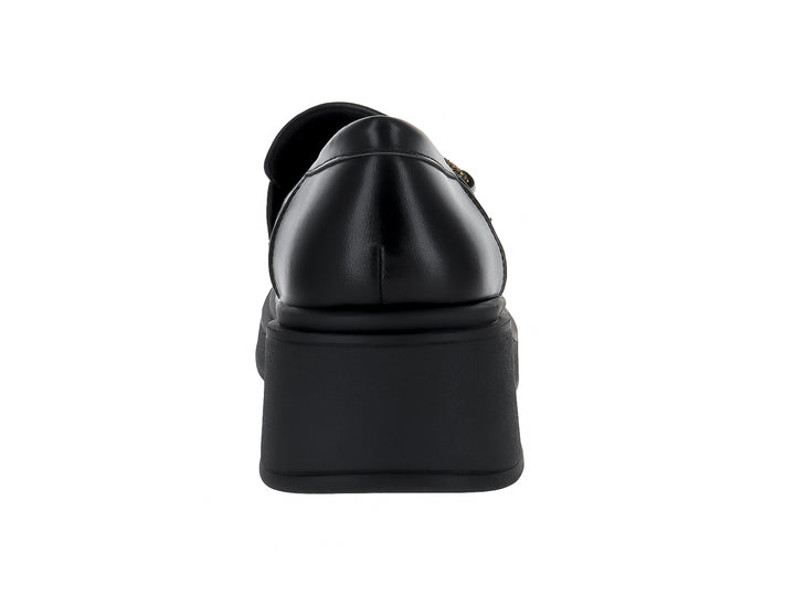 Zapato tipo mocasín negro de material sintético con suela de plataforma gruesa y adorno dorado superior.
