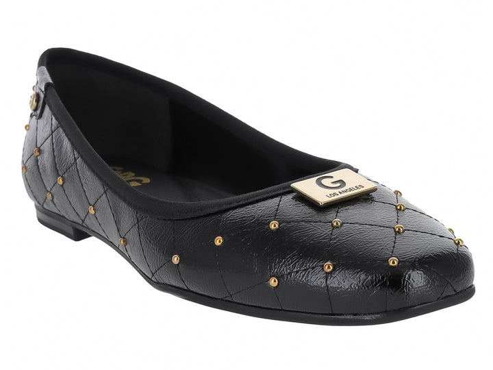 Zapato plano negro con diseño acolchado y tachuelas doradas decorativas.