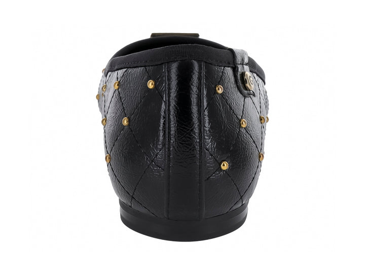 Zapato plano negro con diseño acolchado y tachuelas doradas decorativas.