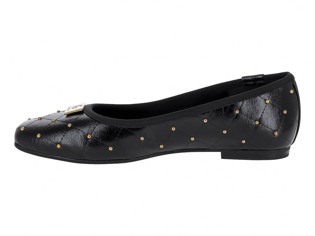 Zapato plano negro con diseño acolchado y tachuelas doradas decorativas.