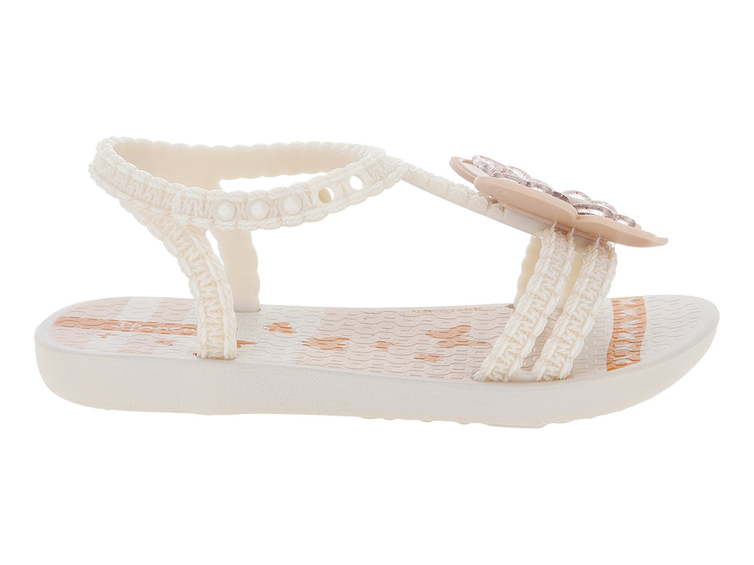 Sandalias para bebé de color beige con adorno de flor y tiras texturizadas.