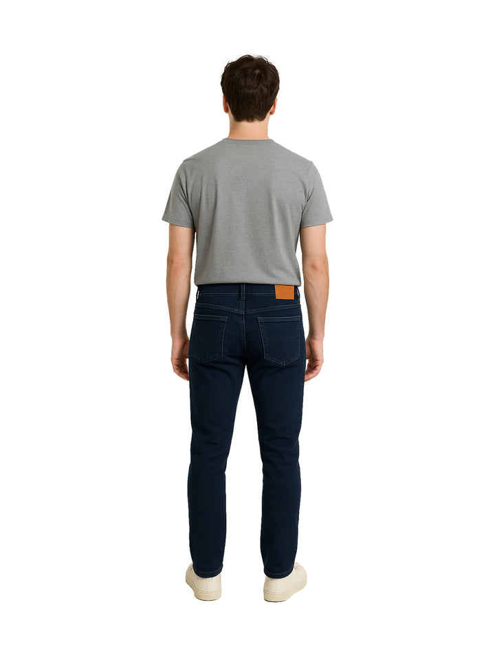 Hombre vistiendo pantalones jeans color azul marino oscuro de corte casual.