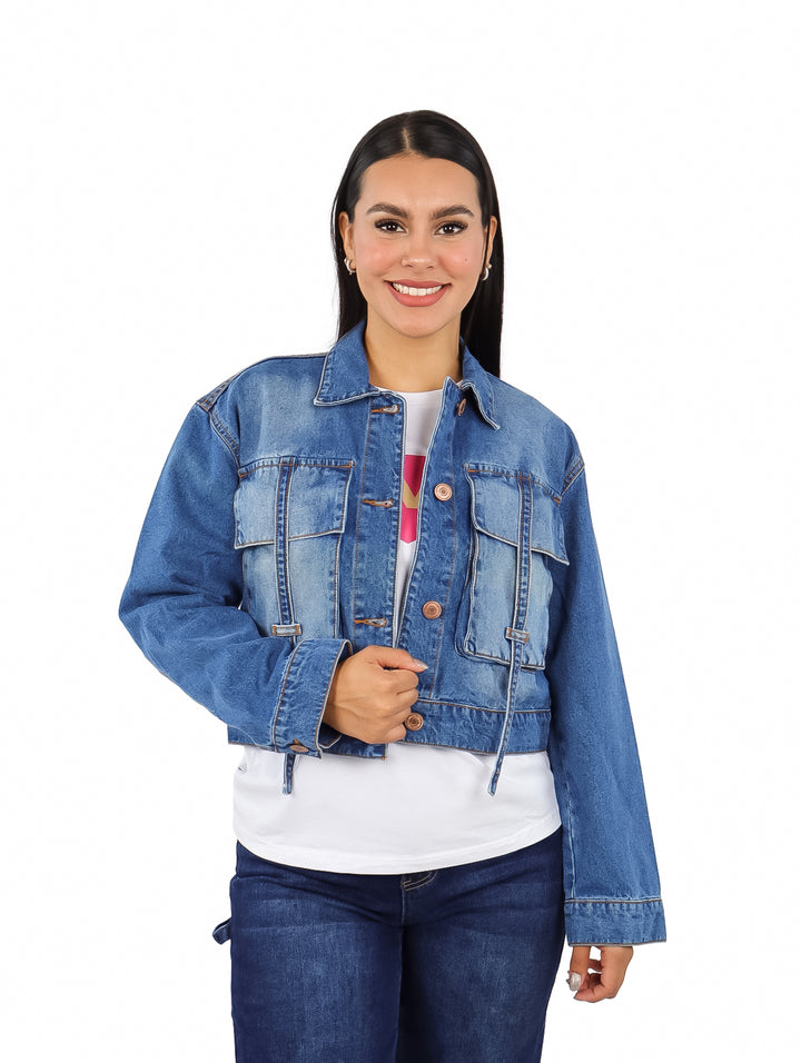 Mujer vistiendo una chamarra corta de mezclilla azul con botones frontales.
