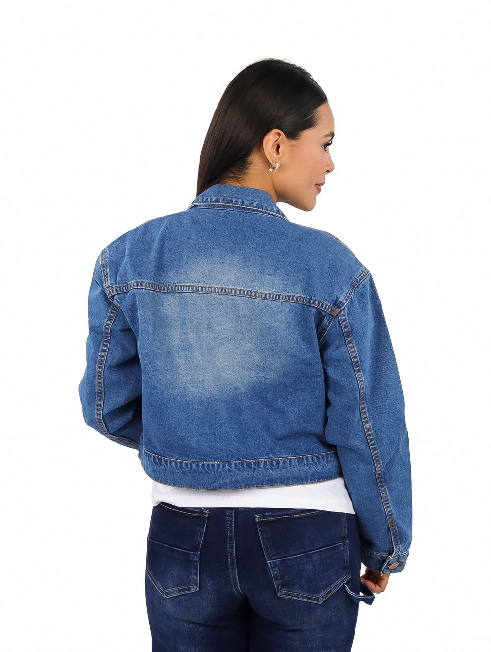 Mujer vistiendo una chamarra corta de mezclilla azul con botones frontales.