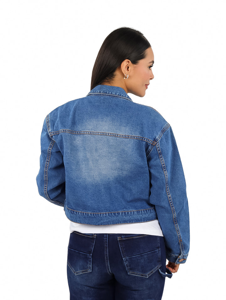 Mujer vistiendo una chamarra corta de mezclilla azul con botones frontales.