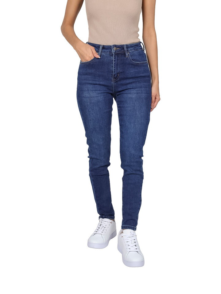 Mujer vistiendo pantalones jeans skinny de color azul oscuro con cintura alta y tenis blancos.