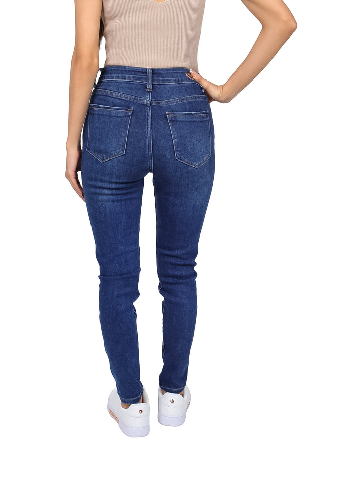 Mujer vistiendo pantalones jeans skinny de color azul oscuro con cintura alta y tenis blancos.