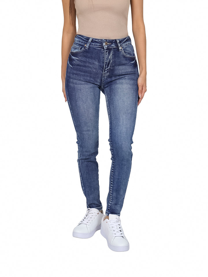 Mujer vistiendo jeans skinny de cintura alta en color azul stone y tenis blancos.