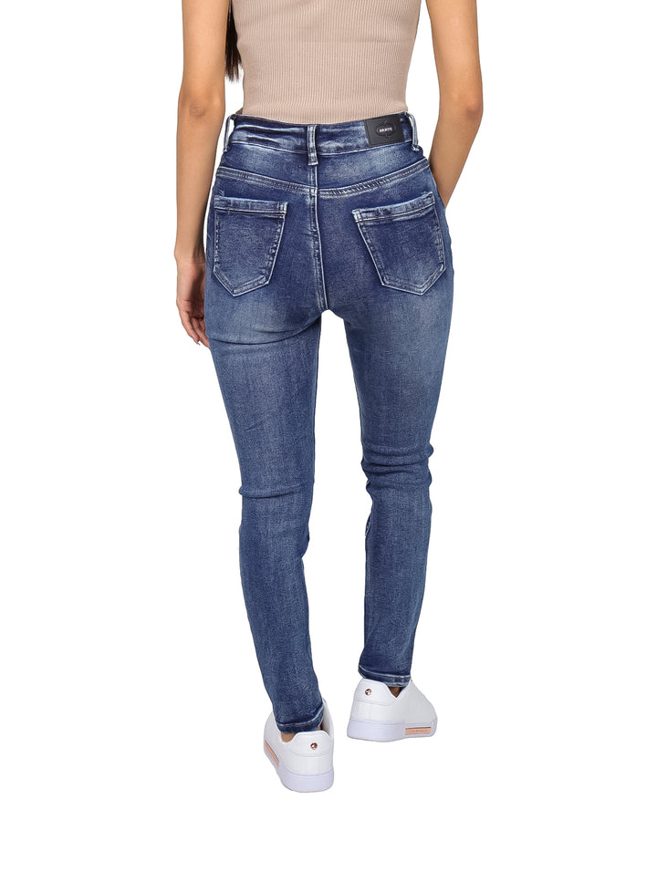 Mujer vistiendo jeans skinny de cintura alta en color azul stone y tenis blancos.