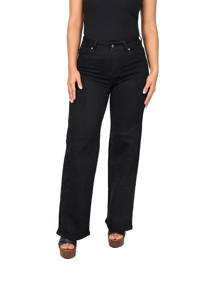 Mujer vistiendo pantalones jeans negros de corte recto con detalles de piedras brillantes.