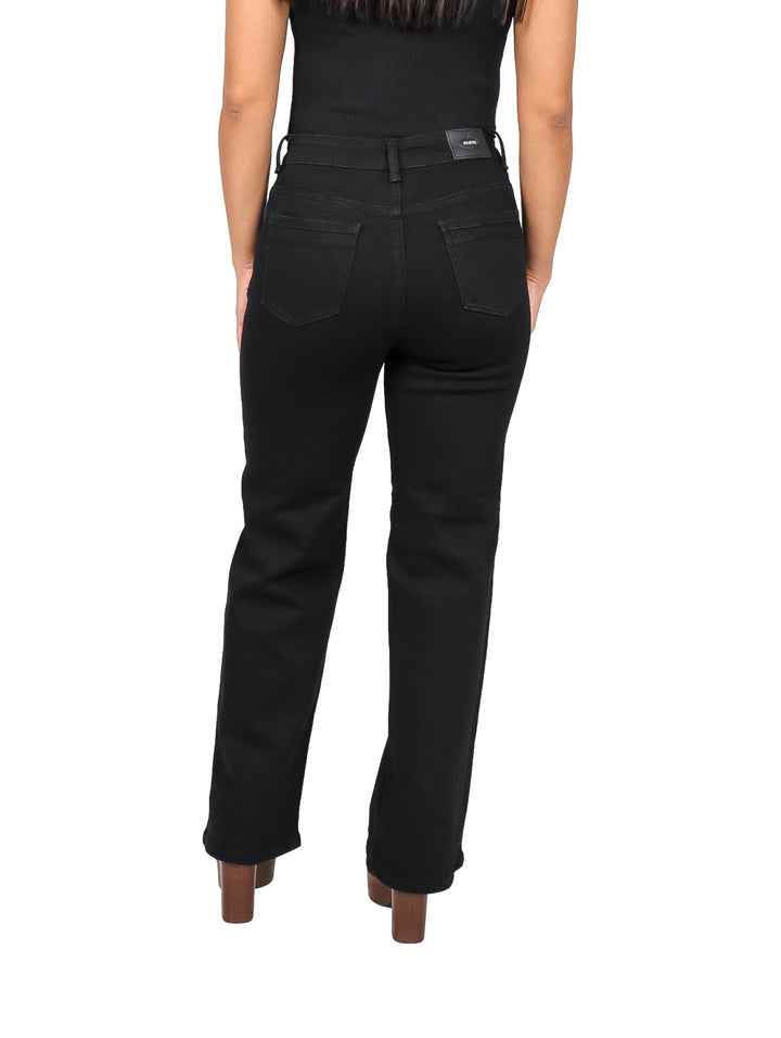 Mujer vistiendo pantalones jeans negros de corte recto con detalles de piedras brillantes.