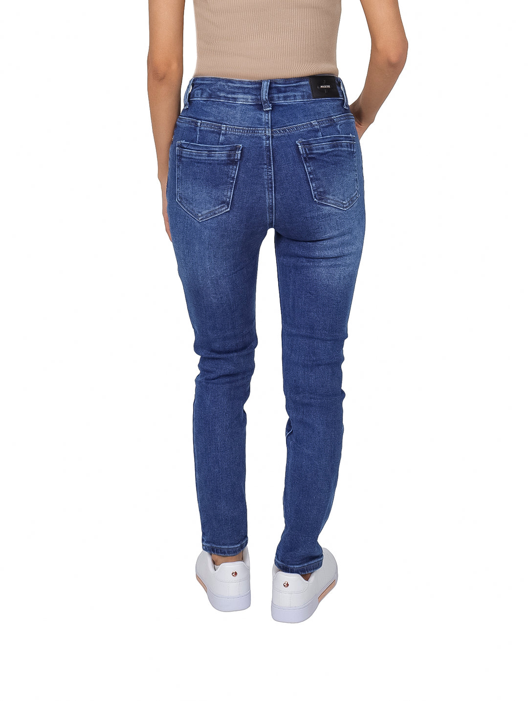Mujer vistiendo pantalones jeans skinny de color azul con cintura alta y tenis blancos.