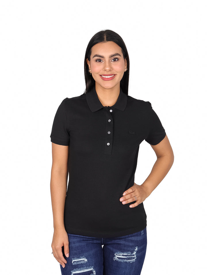 Mujer vistiendo una playera polo Lacoste de color negro y jeans azules.