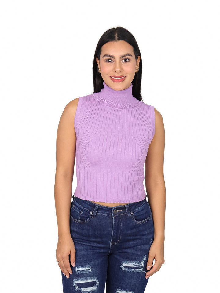 Mujer vistiendo blusa morada sin mangas con cuello tortuga y pantalones de mezclilla.