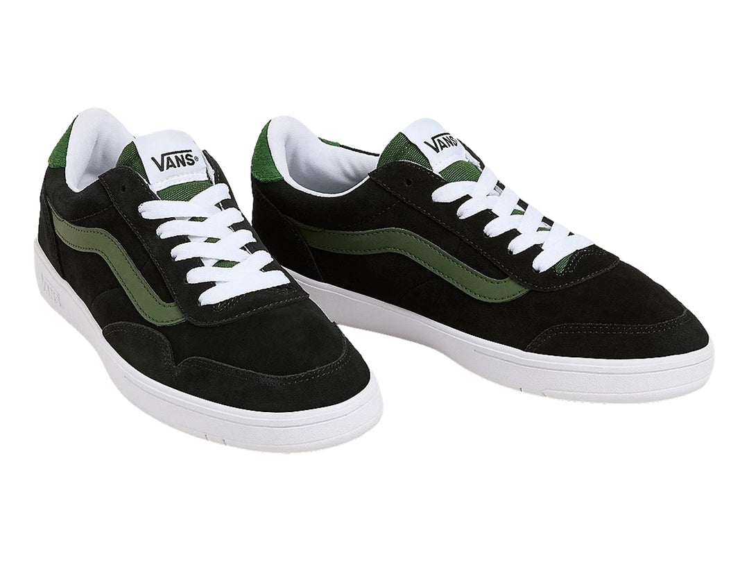 Tenis VANS color negro con franja lateral verde y suela blanca.