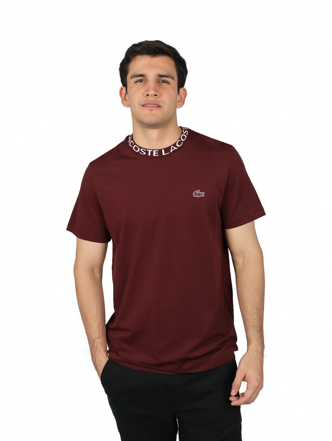 Hombre vistiendo camiseta Lacoste color expresso con banda blanca en el cuello y logotipo en el pecho.