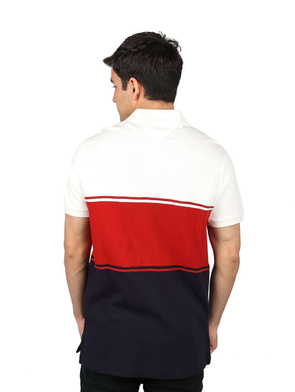 Hombre vistiendo polo Tommy Hilfiger con bloques de color blanco, rojo y azul marino.