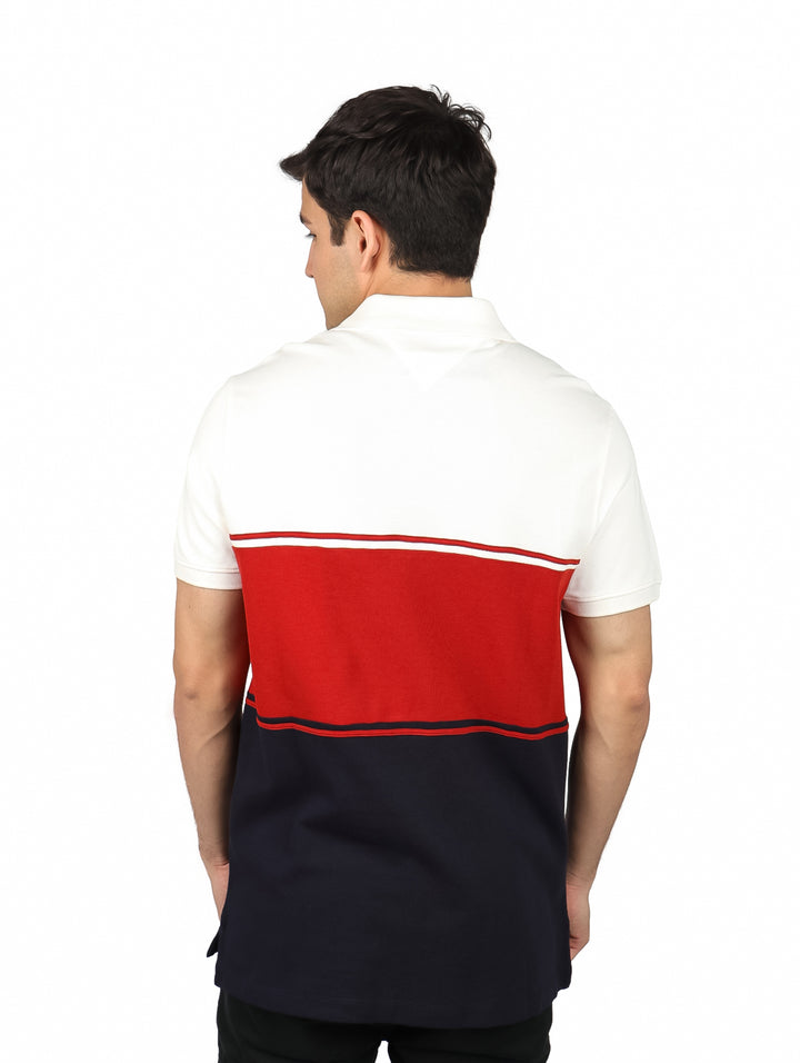 Hombre vistiendo polo Tommy Hilfiger con bloques de color blanco, rojo y azul marino.