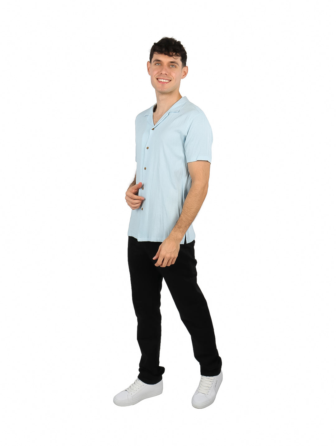 Hombre vistiendo una camisa de manga corta color azul cielo y pantalones negros sobre fondo blanco.