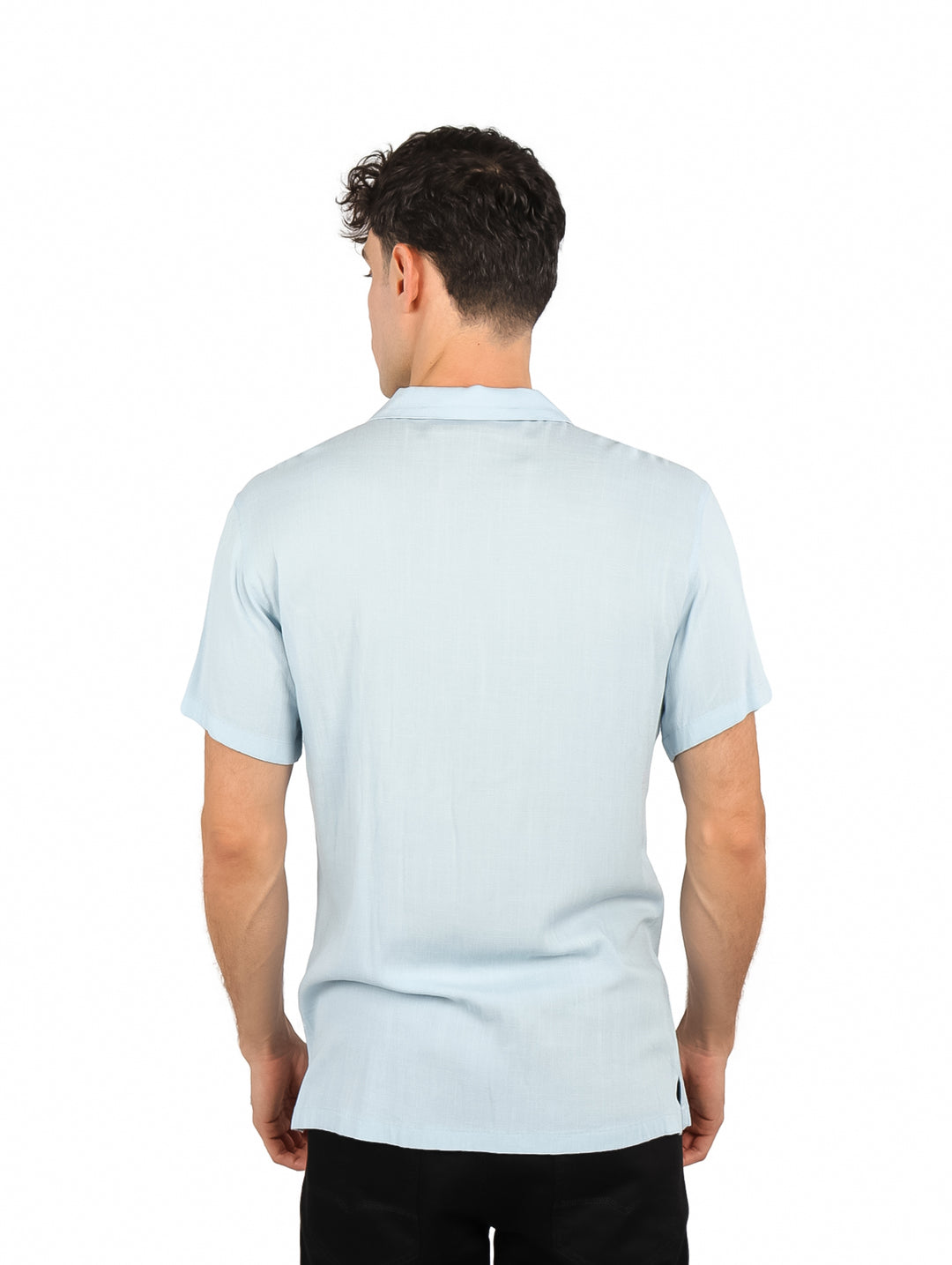 Hombre vistiendo una camisa de manga corta color azul cielo y pantalones negros sobre fondo blanco.