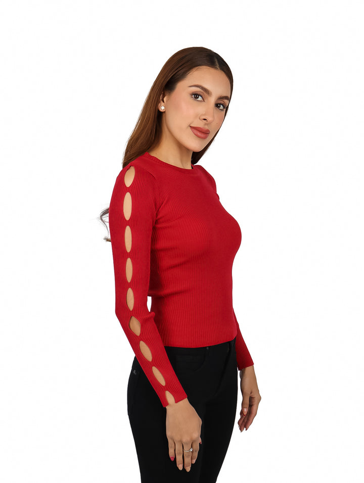 Mujer vistiendo un suéter rojo tejido con recortes en la manga y pantalones negros.