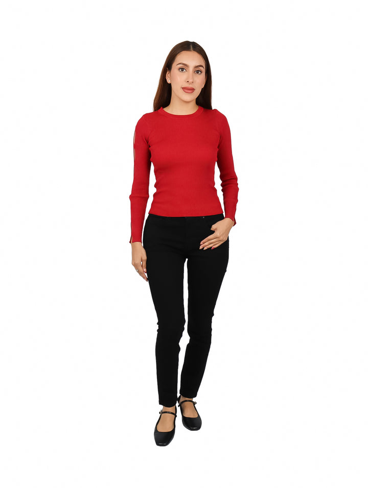 Mujer vistiendo un suéter rojo tejido con recortes en la manga y pantalones negros.