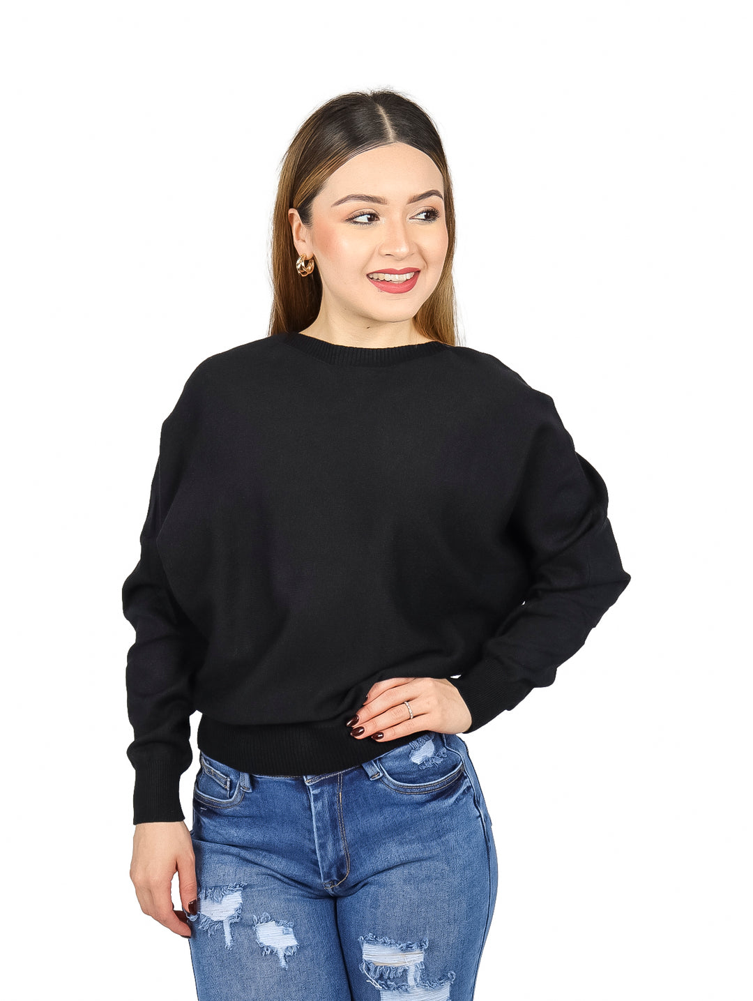 Mujer vistiendo un suéter ancho de color negro y pantalones mezclilla azules.
