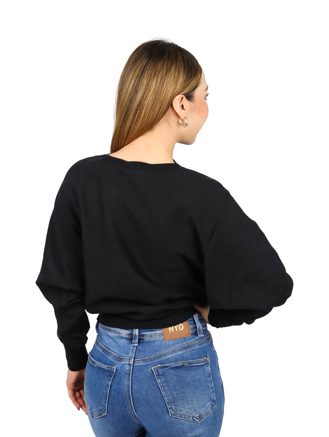 Mujer vistiendo un suéter ancho de color negro y pantalones mezclilla azules.