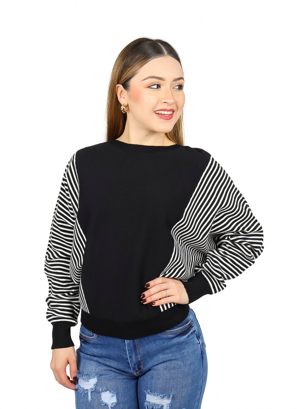 Mujer vistiendo un suéter negro con mangas a rayas blancas y negras y jeans azules.