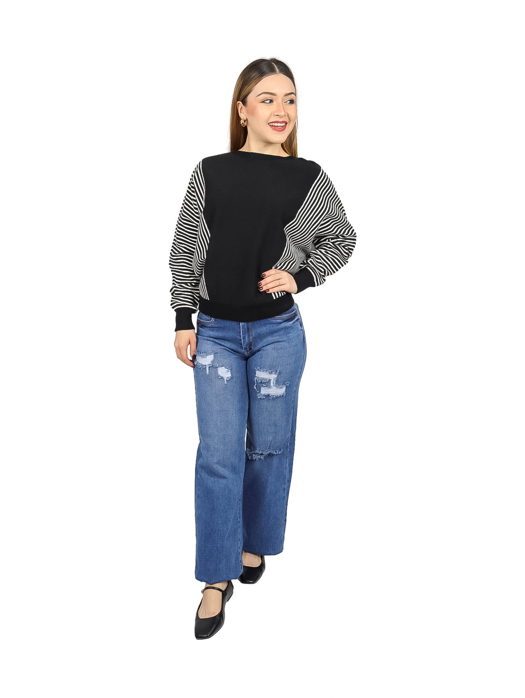 Mujer vistiendo un suéter negro con mangas a rayas blancas y negras y jeans azules.