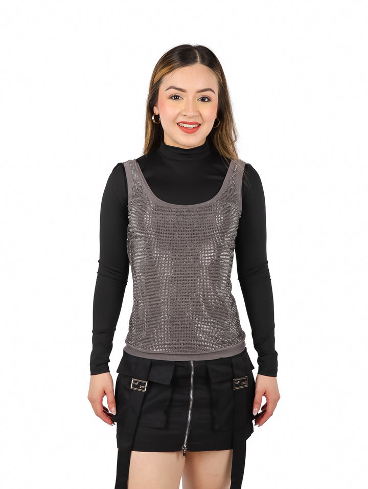 Mujer vistiendo blusa gris con brillos y mangas largas negras sobre fondo blanco.