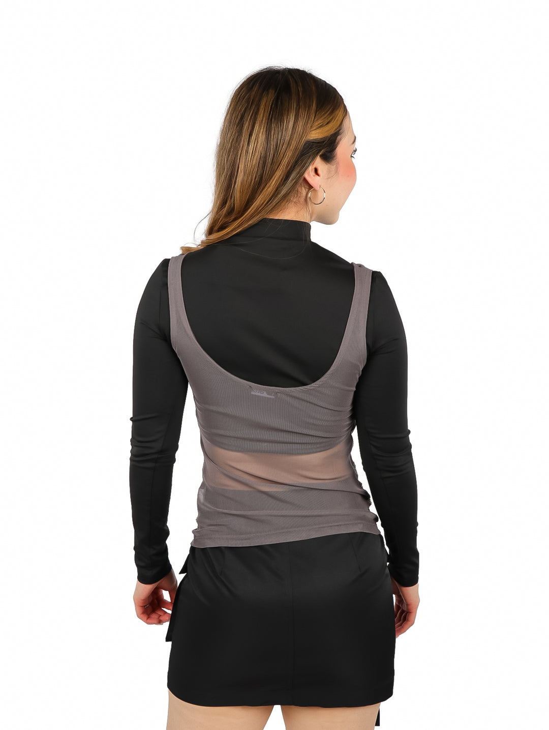 Mujer vistiendo blusa gris con brillos y mangas largas negras sobre fondo blanco.