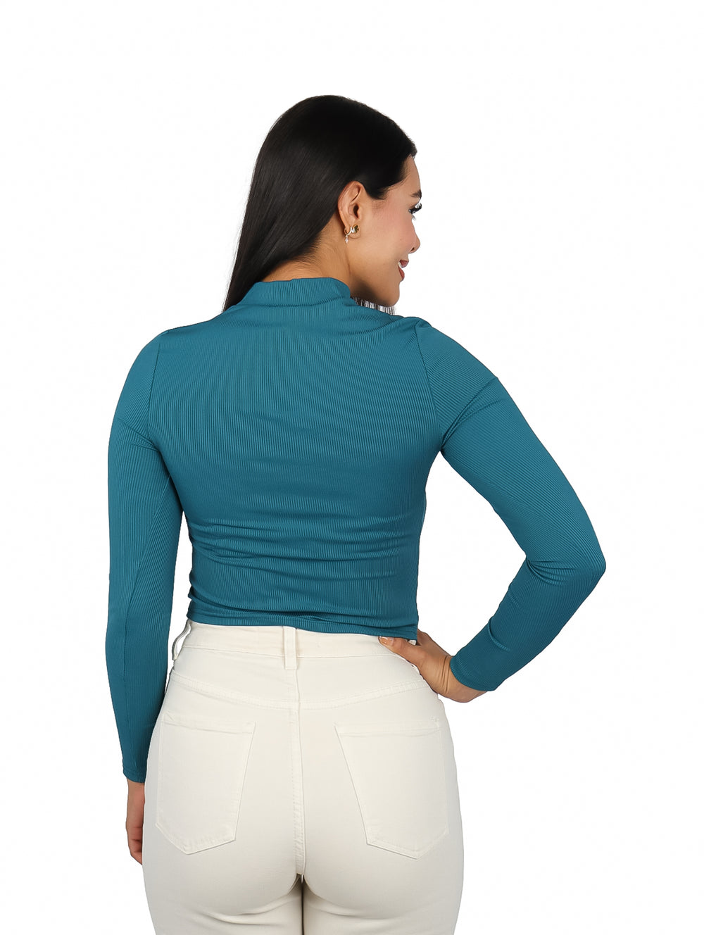 Mujer vistiendo blusa verde de manga larga con escote en el pecho y pantalones blancos.