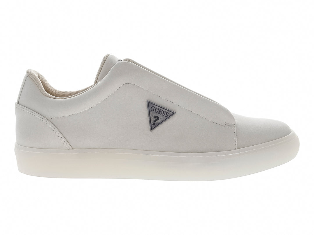 Tenis casuales color beige marca Guess, estilo slip-on con suela blanca y logo lateral.