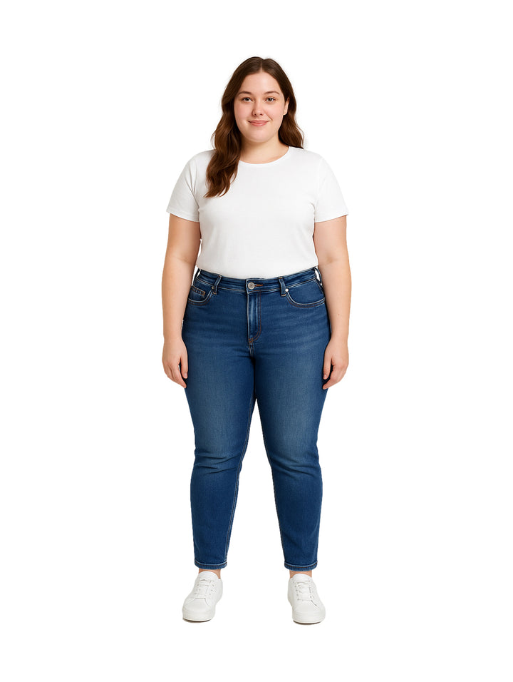 Mujer vistiendo pantalones jeans skinny en color azul oscuro con playera blanca y tenis blancos.