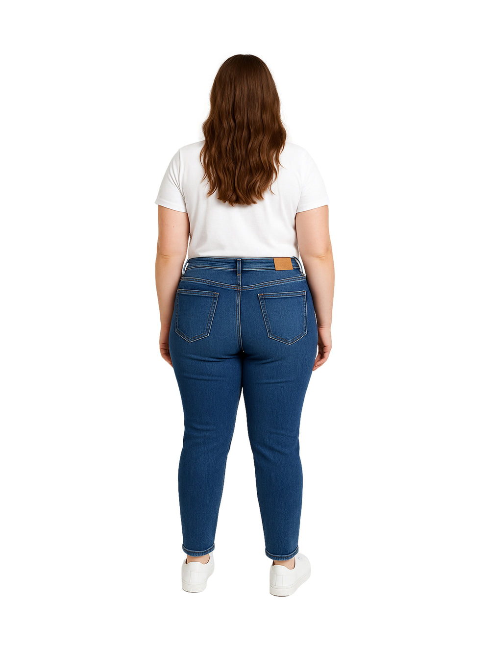 Mujer vistiendo pantalones jeans skinny en color azul oscuro con playera blanca y tenis blancos.