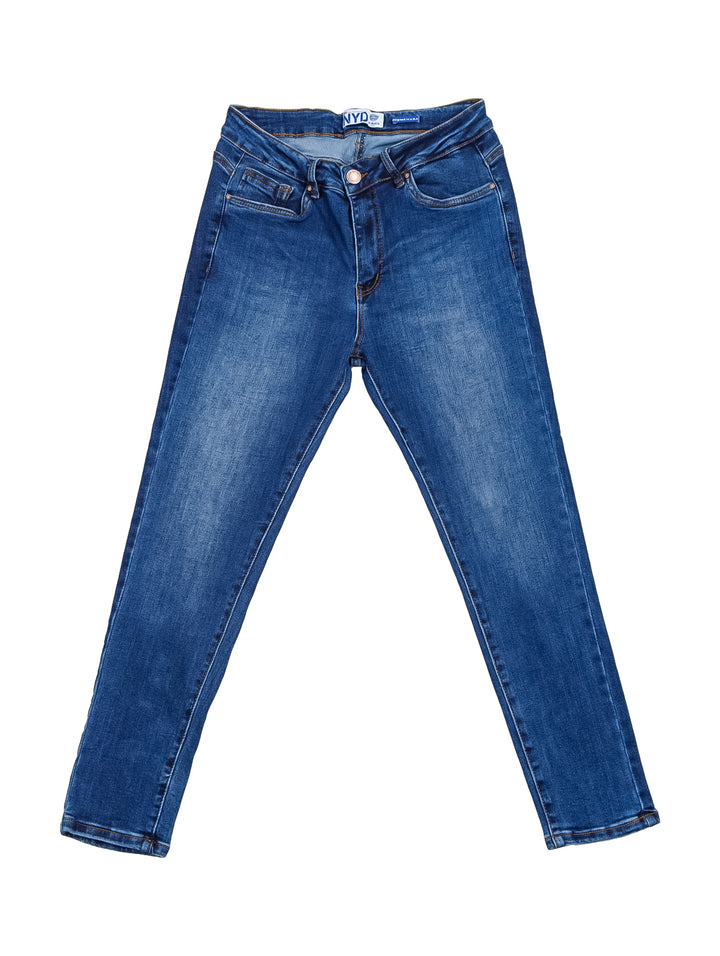 Mujer vistiendo pantalones jeans skinny en color azul oscuro con playera blanca y tenis blancos.