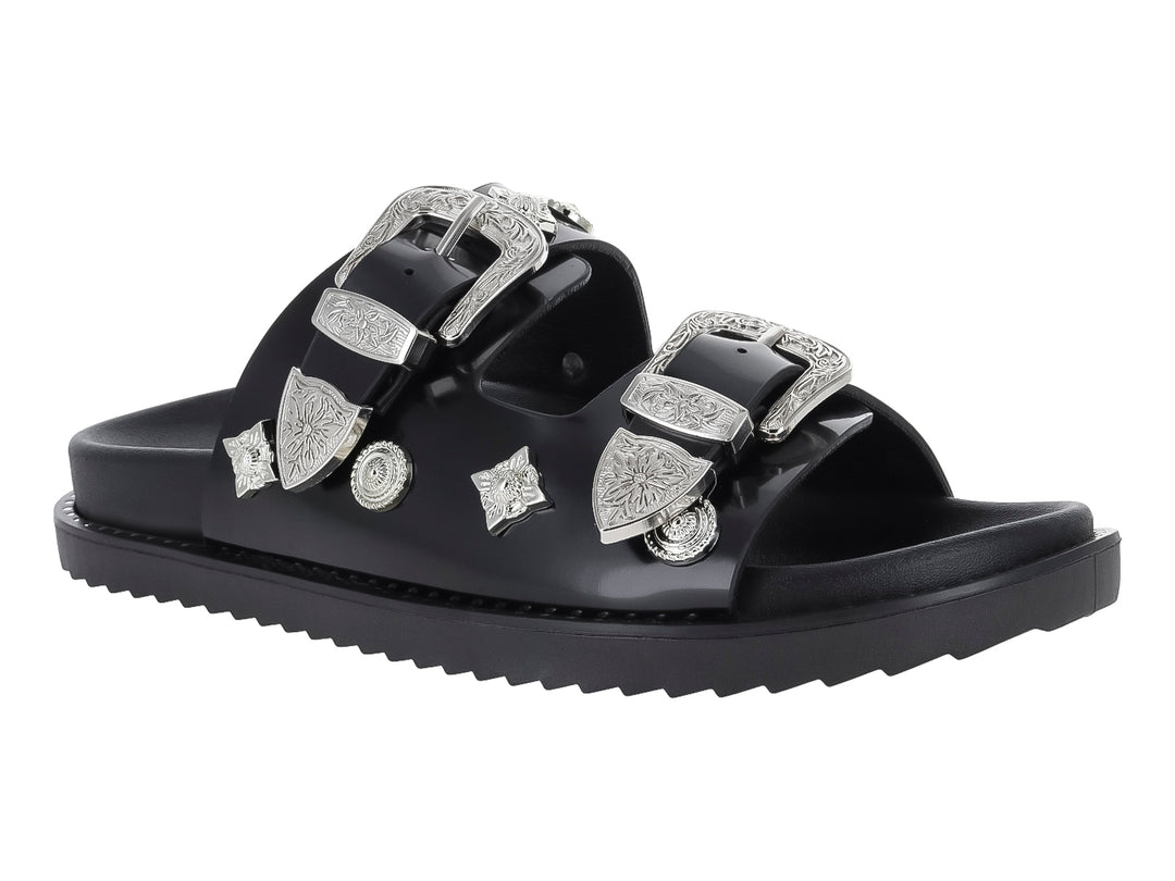 Sandalia negra para mujer con dos correas adornadas con hebillas y detalles ornamentales en color plata.