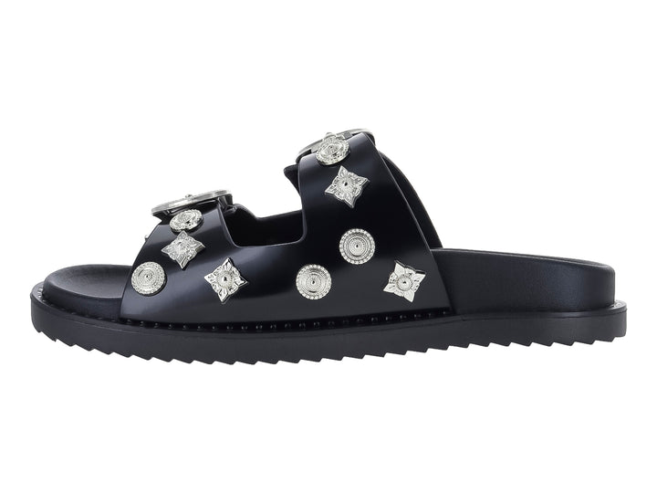 Sandalia negra para mujer con dos correas adornadas con hebillas y detalles ornamentales en color plata.