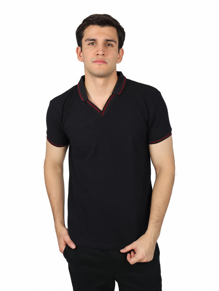 Hombre vistiendo playera polo color negro con detalles rojos en el cuello y mangas.
